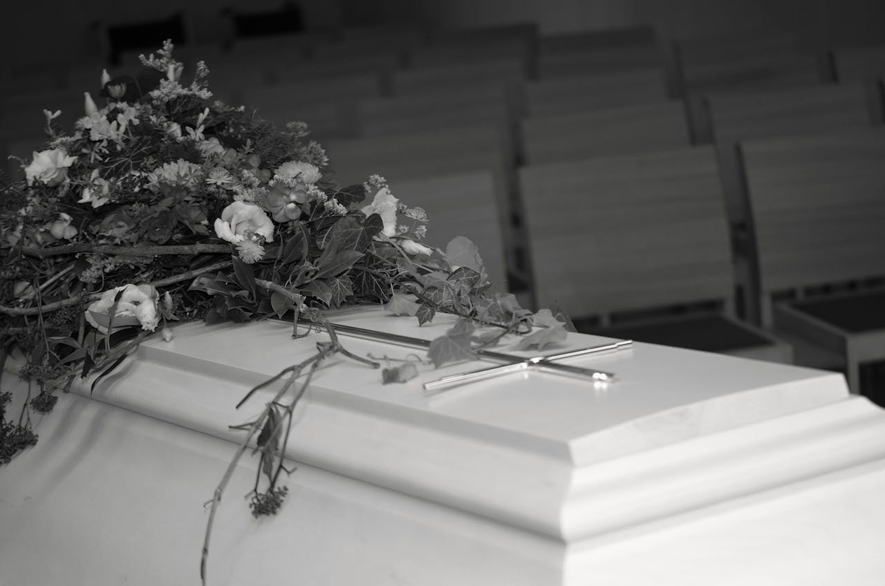 A white casket adorned with flowers inside a serene chapel, evoking calm and reflection.
